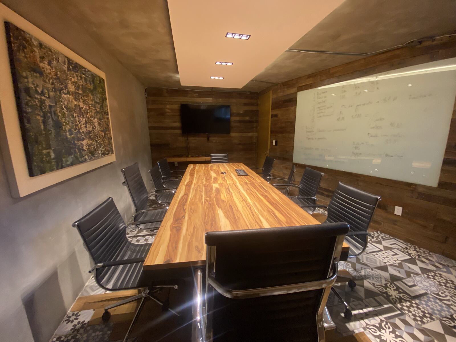 Sala de juntas con mesa de madera y pizarrón